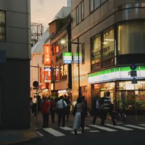 夜の都市でファミマフードドライブを実施するファミリーマート店舗の明かりと行き交う人々の街並み